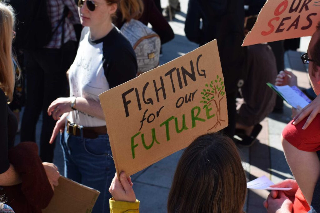 Photo of a climate march, with a sign that says "fighting for our future." Credit Ma Ti.