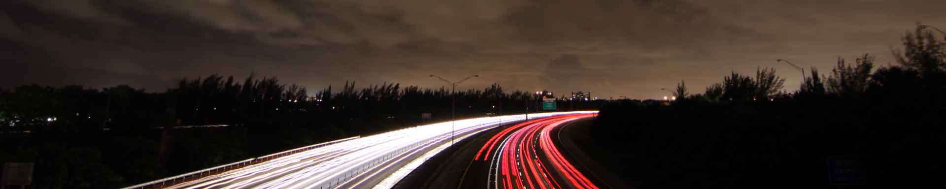 Photo of tail and head lights of traffic on a highway at night. Photo by Alec Attie on Unsplash