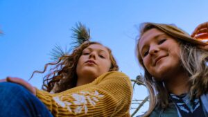 Photo of two young women looking down at the camera. Photo by Adam McCoid on Unsplash