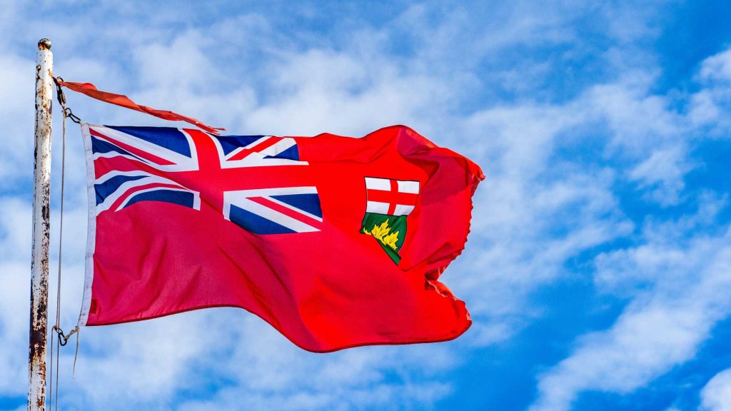 Photo of the flag of Ontario, flying in a strong breeze, with a blue sky and some