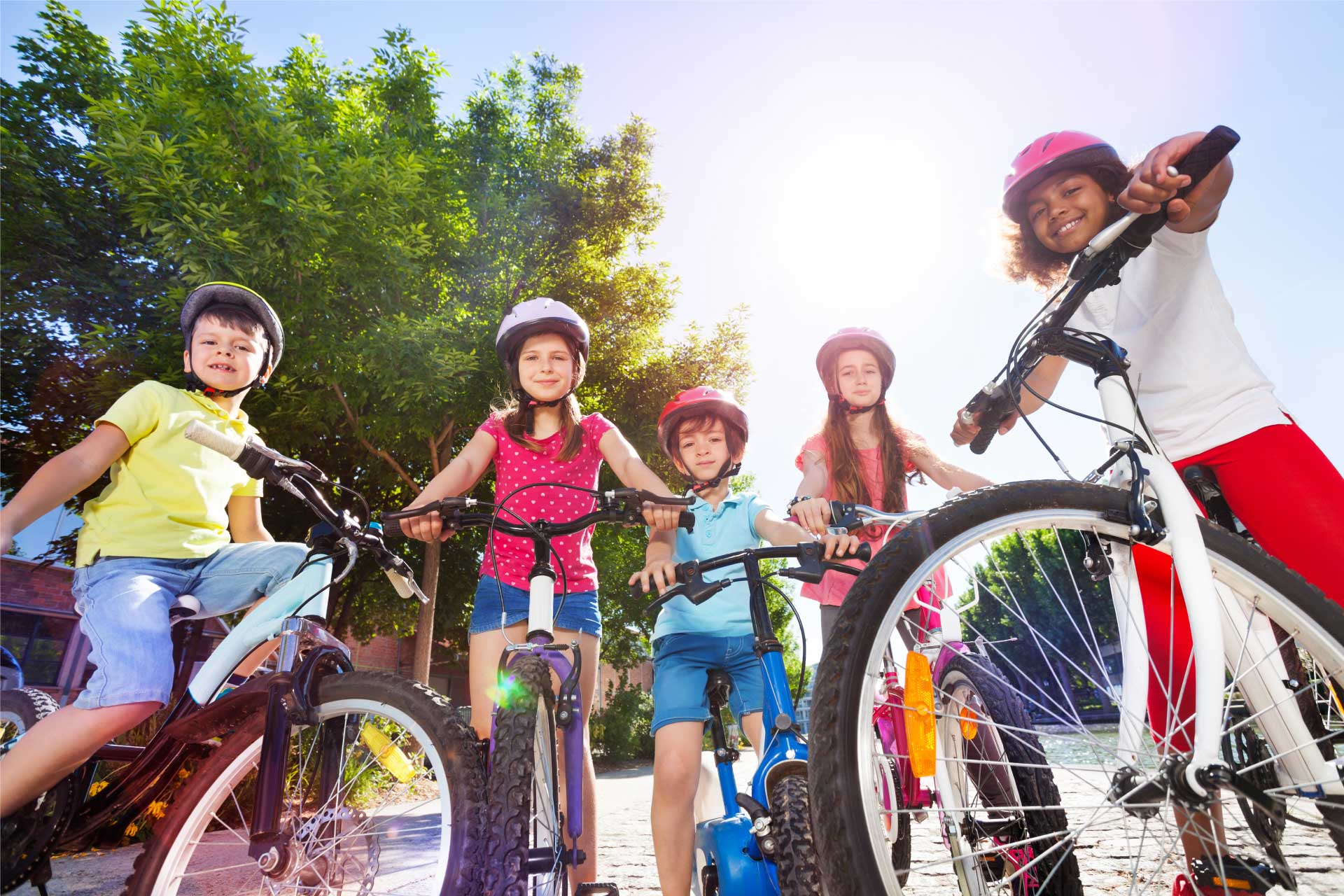 Photo of several kids on bicycles, in a semicircle, looking at the camera.